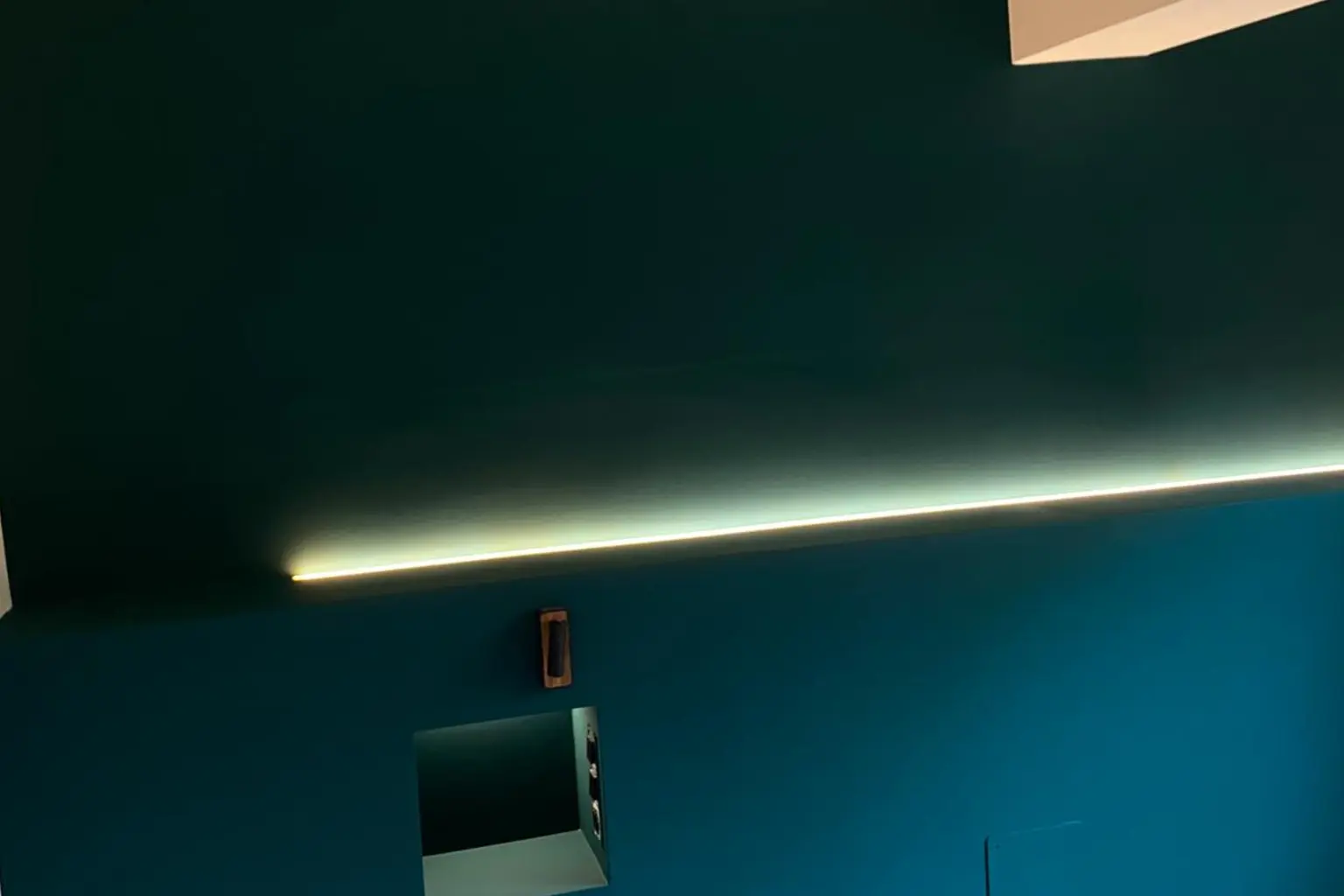 Panel de pared en verde profundo con línea de luz integrada y hornacinas